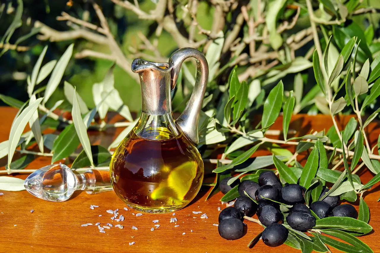 A bottle of olive oil and some olives on the table.